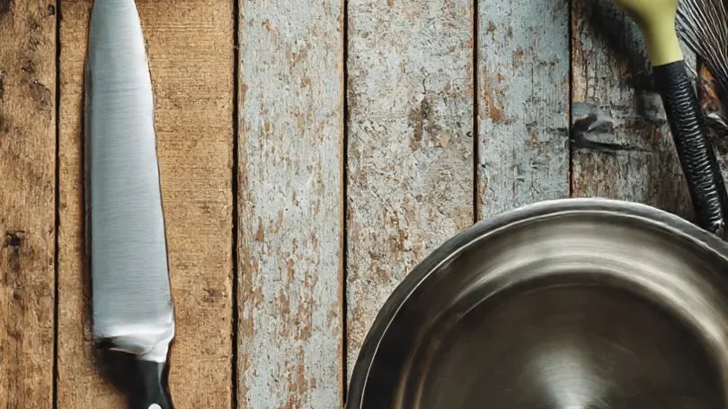 Manos de una cocinera utilizando un cuchillo de chef para picar ingredientes, demostrando el proceso de preparación en la cocina.