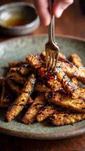 Plato de berenjenas fritas en freidora de aire con miel de caña listas para comer.